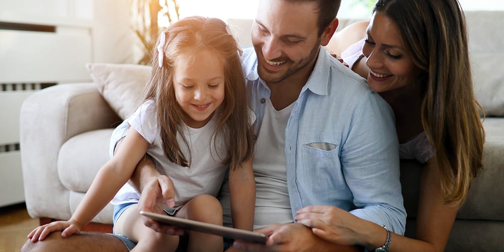 little girl looking at an iPad with her mother and father