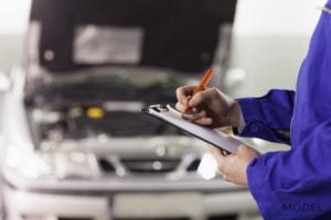 Mechanic Writing Notes About Car He is Repairing